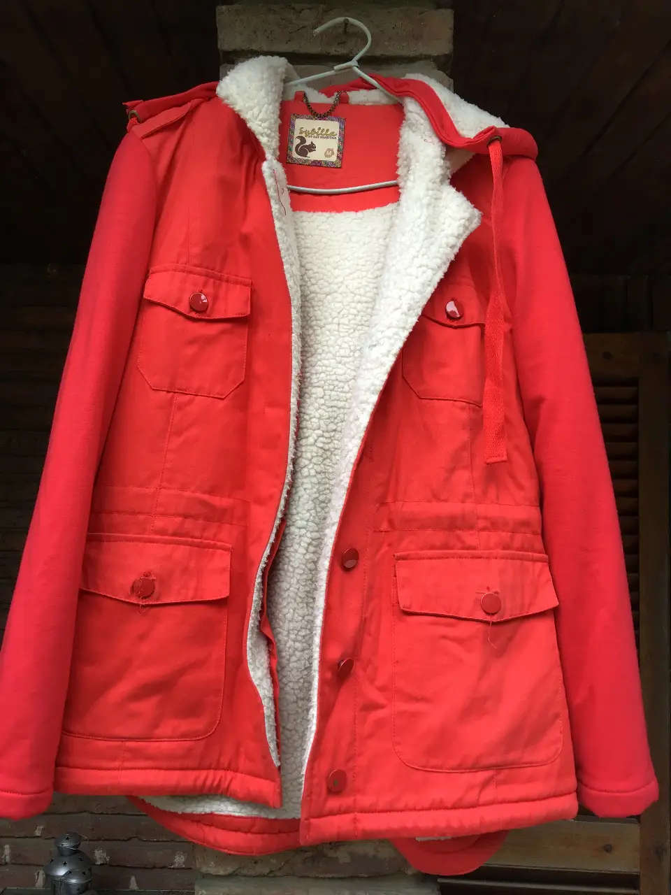 Campera roja con capucha y forro de piel sintética blanca. Ideal para el invierno, con bolsillos amplios y botones. Estilo casual y abrigado.