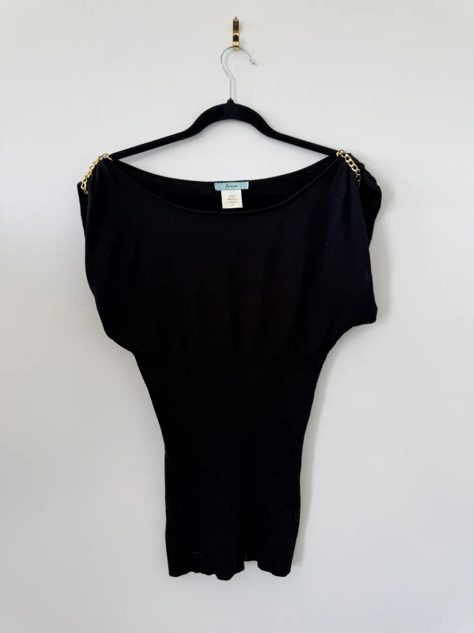 Top negro con detalles de cadenas doradas en los hombros. Diseño elegante y moderno, ideal para lucir sofisticada en cualquier salida.