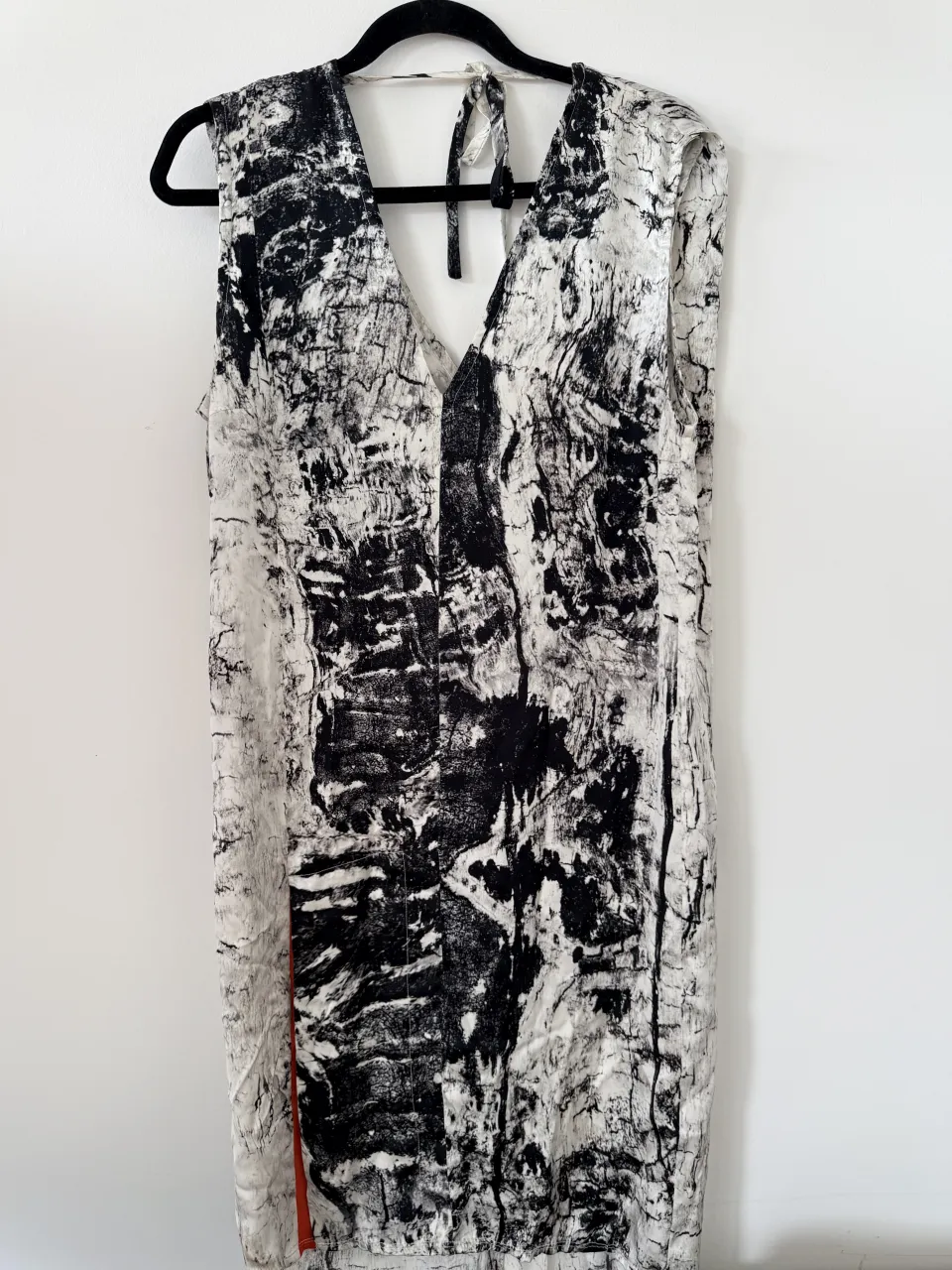 Vestido estampado blanco y negro con detalles en naranja. Diseño abstracto y moderno, ideal para un look casual y chic. Espalda escotada con tiras.