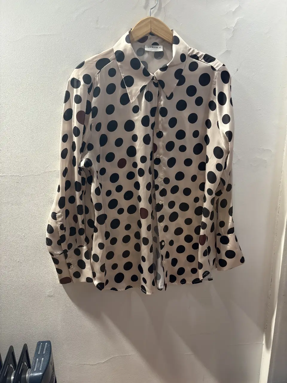 Camisa de mujer con estampado de lunares grandes en blanco y negro. Ideal para un look casual o para darle un toque divertido a tu outfit de trabajo. Confeccionada en un tejido ligero y fluido.