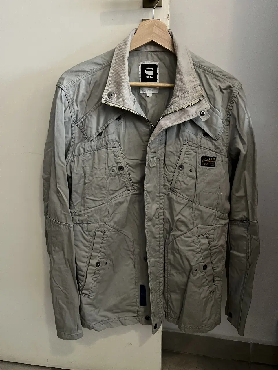 Campera G-Star RAW gris, con múltiples bolsillos y detalles de diseño utilitario. Ideal para un look casual y moderno.