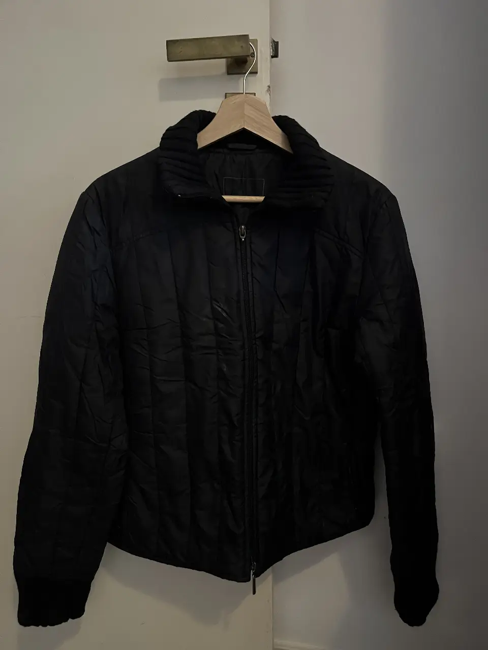 Campera negra acolchada con cierre frontal y cuello alto. Ideal para el invierno, con un diseño clásico y versátil.