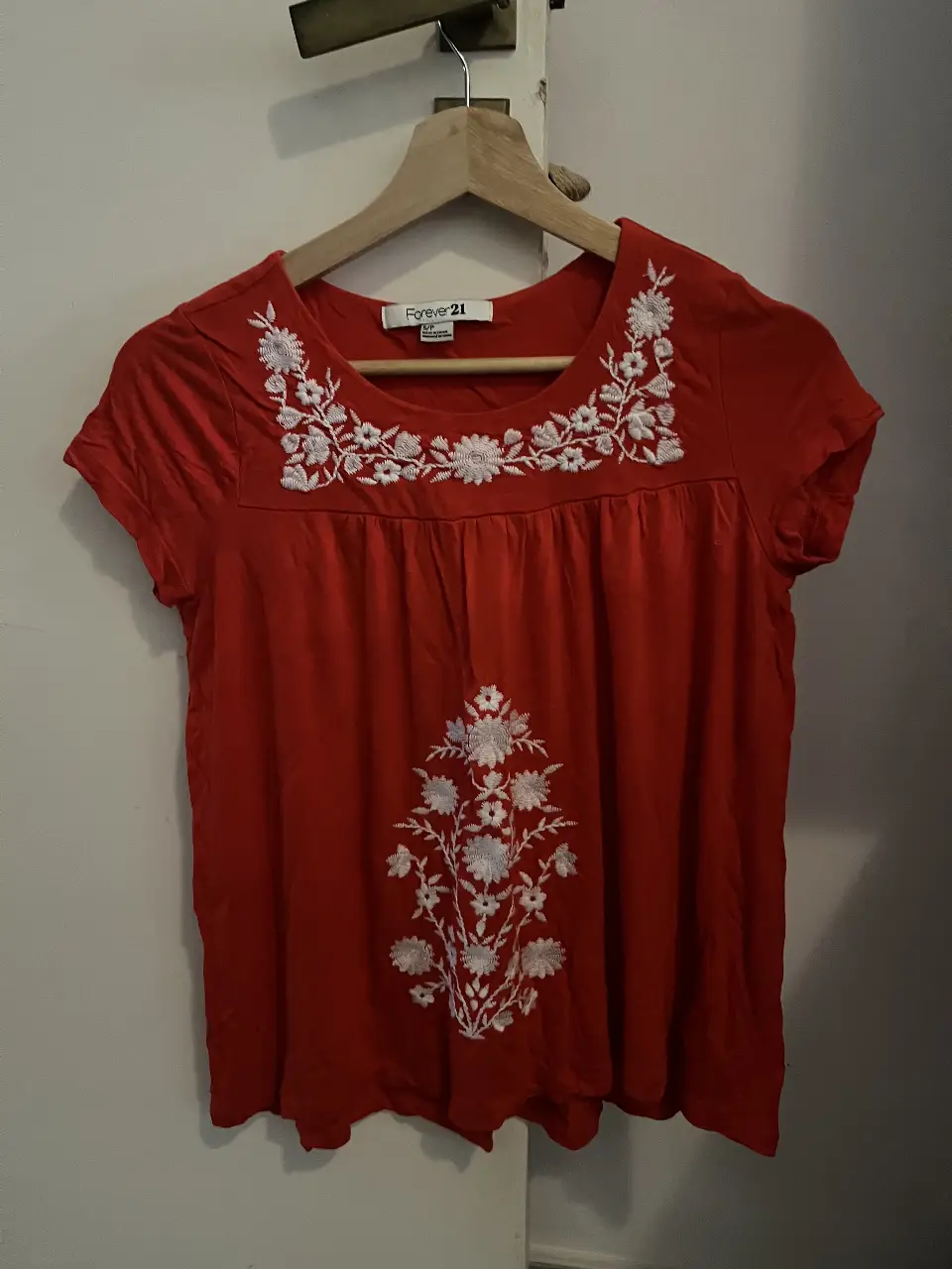 Blusa roja de Forever 21 con bordado floral blanco en el cuello y el centro. Manga corta, ideal para un look casual y fresco.