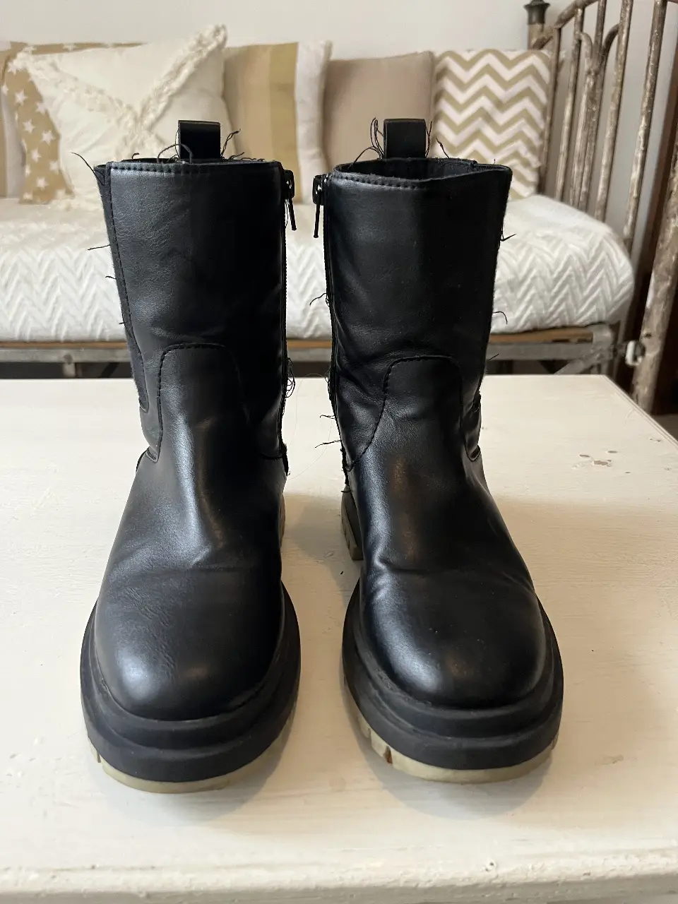 Botines negros de cuero sintético con suela gruesa. Tienen cierre lateral y detalles de costura. Ideales para un look casual y moderno.