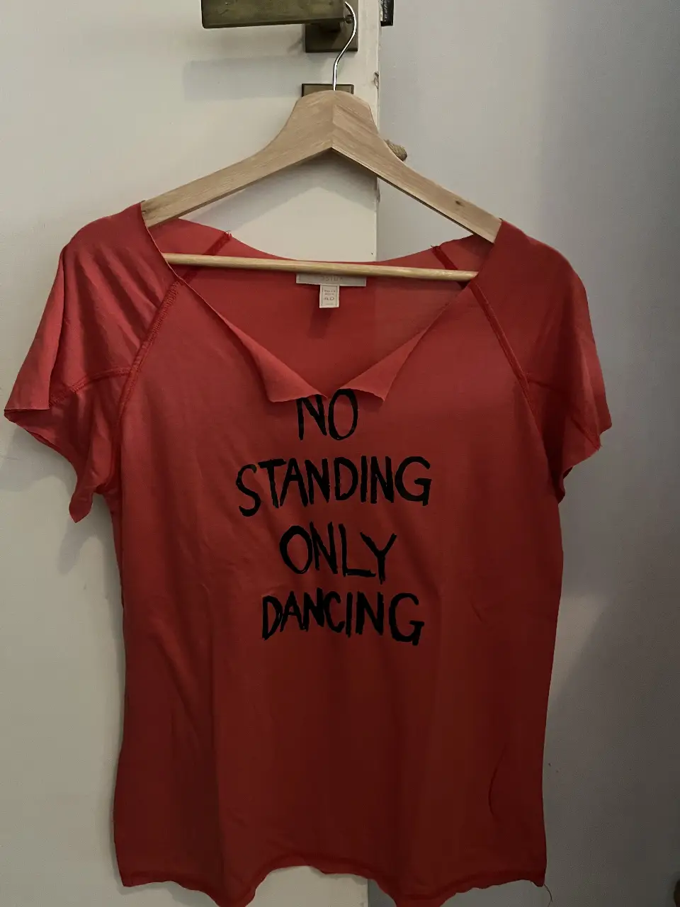 Remera roja con estampado "NO STANDING ONLY DANCING". Cuello irregular y mangas cortas. Ideal para un look casual y con onda.