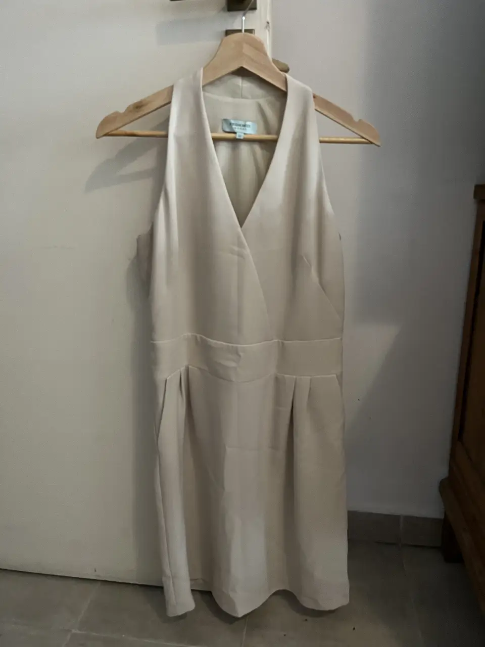 Vestido midi color crudo, con escote en V y detalle de pliegues en la cintura. Ideal para eventos formales o salidas.