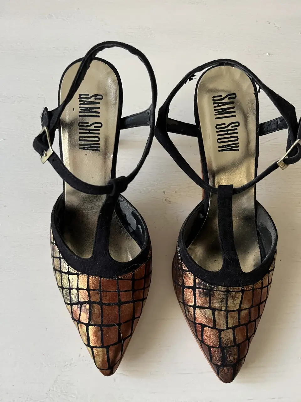 Elegantes zapatos de taco alto con diseño de mosaicos dorados y detalles en negro. Ideales para fiestas y eventos especiales.