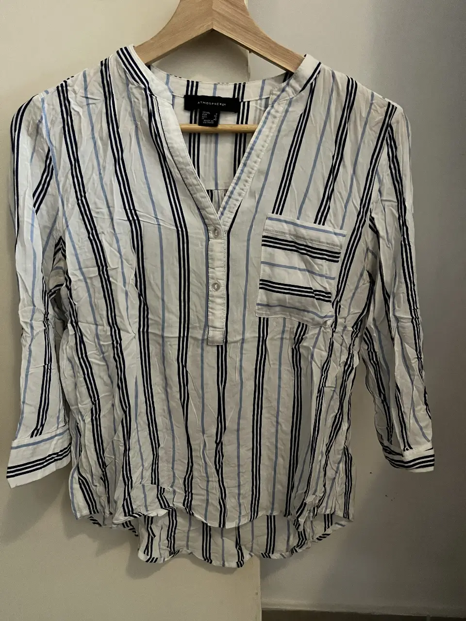 Blusa de mujer a rayas verticales en blanco y azul, con cuello en V y bolsillo en el pecho. Talle S.