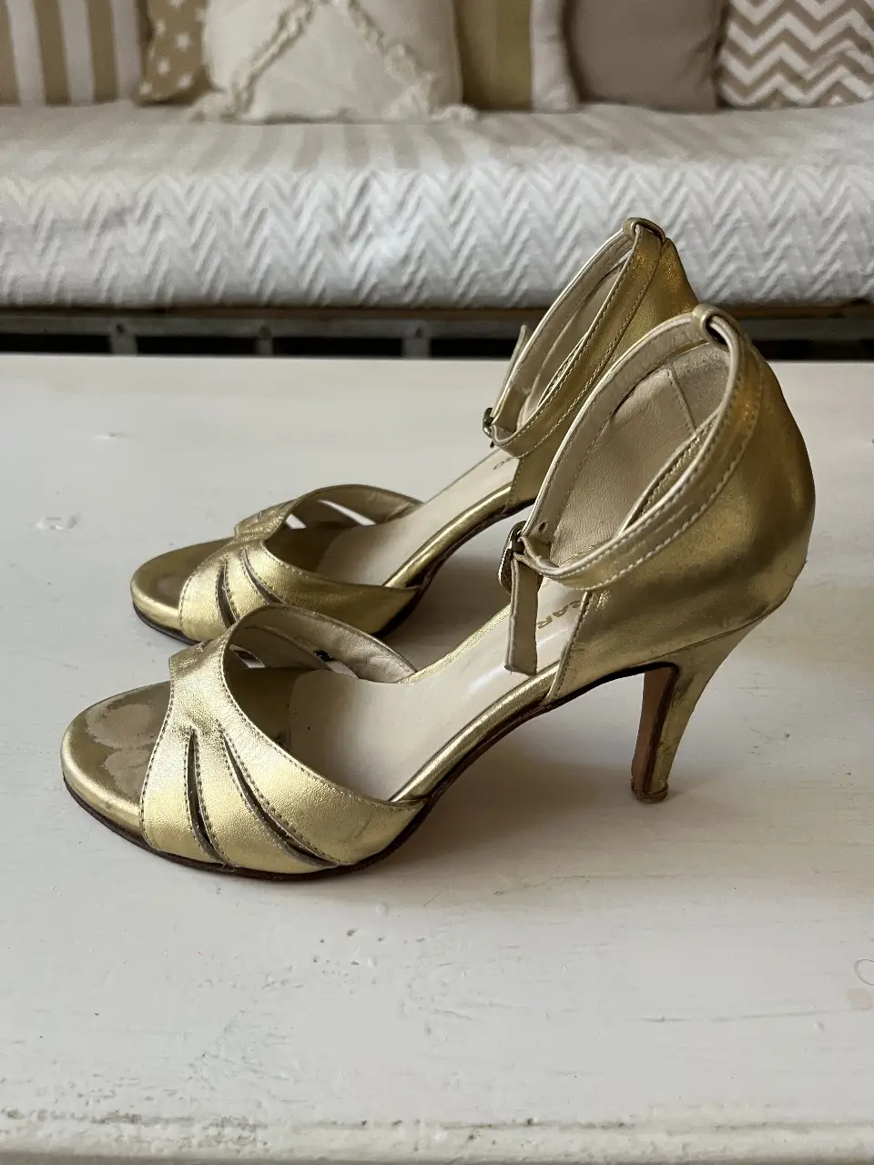 Sandalias doradas de fiesta con taco fino y pulsera al tobillo. Ideales para eventos especiales.