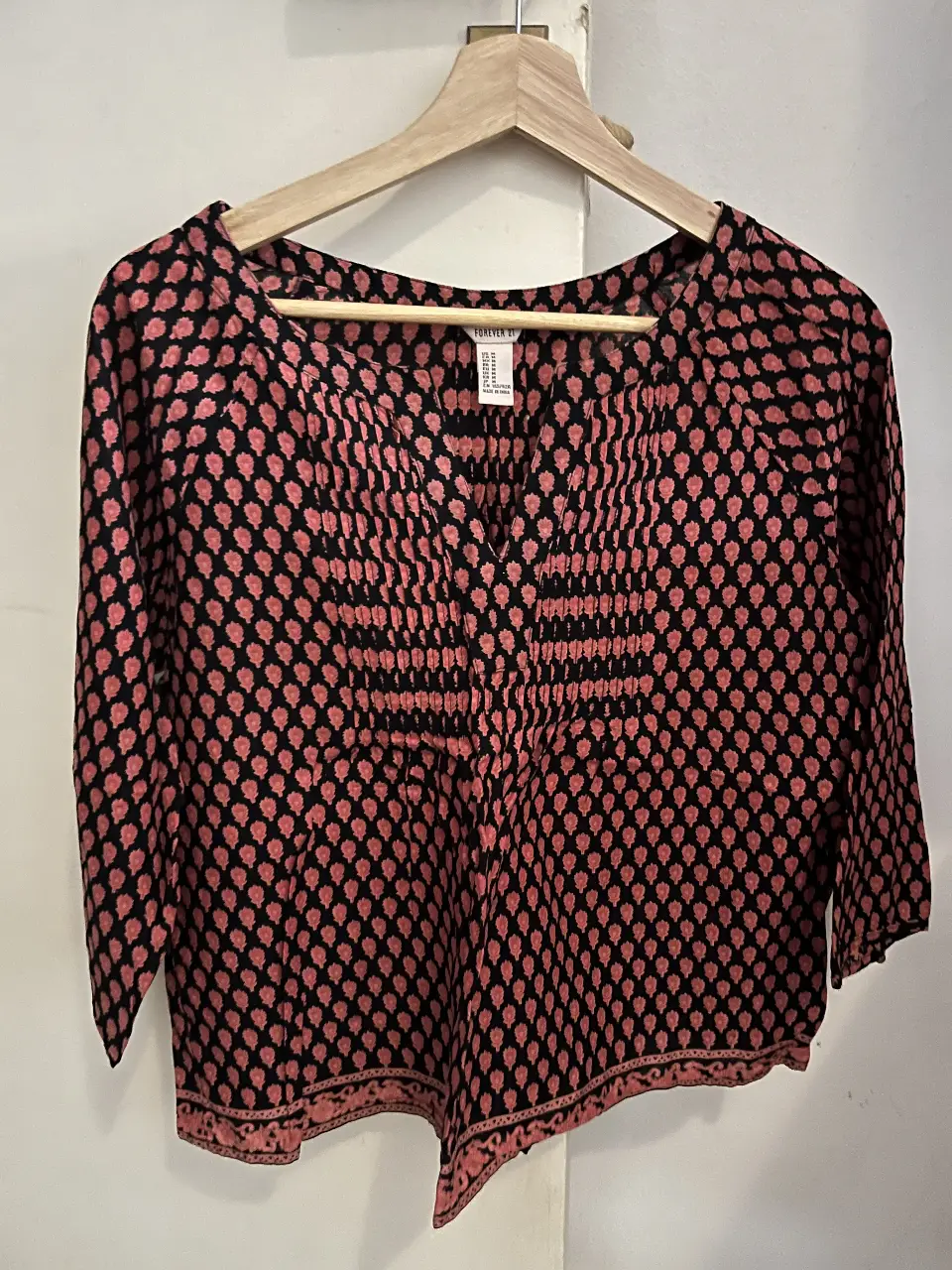 Blusa de Forever 21 con estampado floral en tonos rosa y negro. Manga 3/4 y detalle de fruncido en el frente. Ideal para un look casual y femenino.
