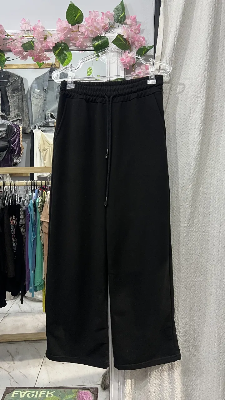 Pantalón suelto de tela negra con cintura elastizada y cordón. Ideal para un look casual y cómodo.