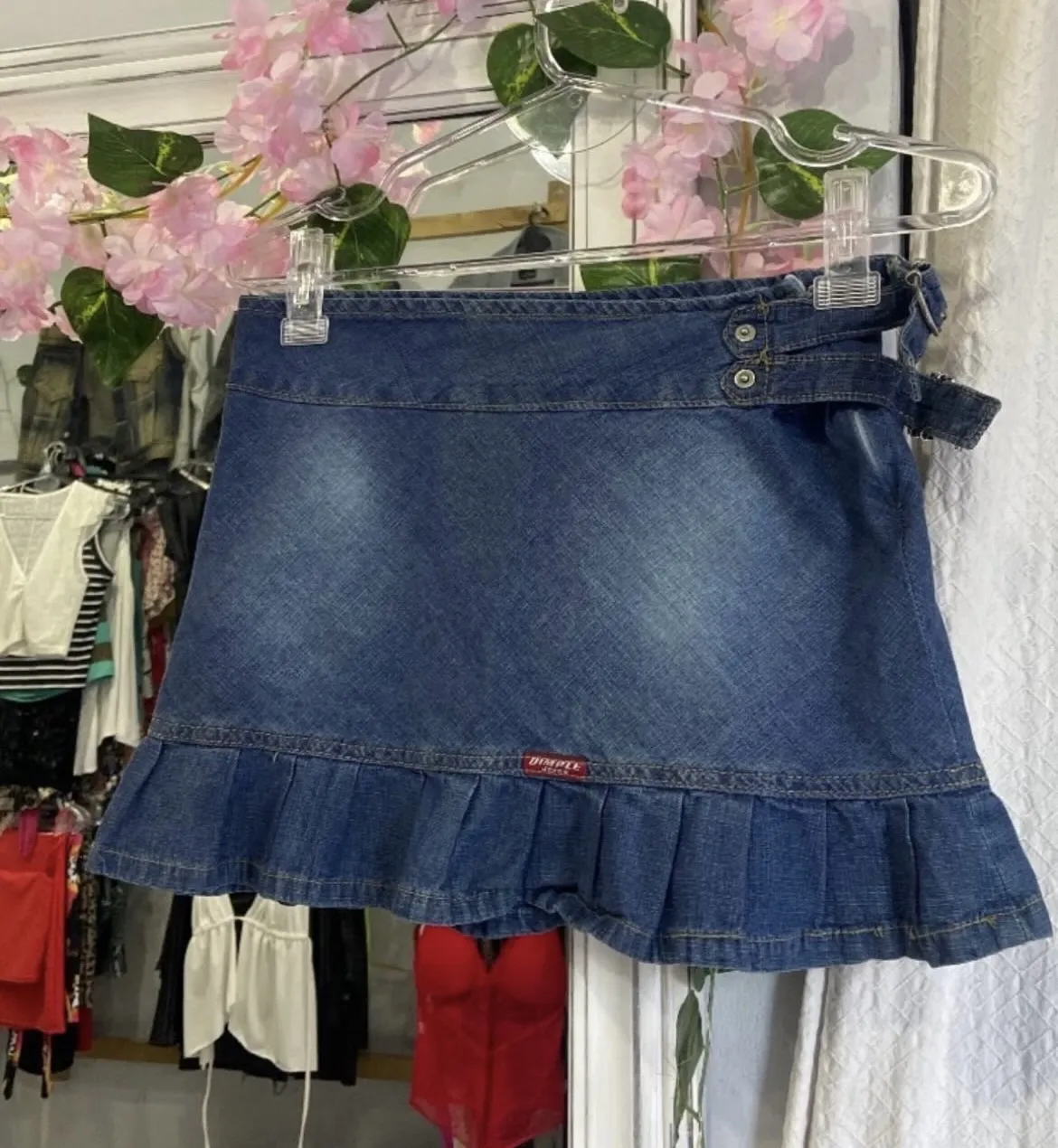 Minifalda de jean azul con detalle de volados en el borde inferior. Diseño Y2K con detalles de botones y cinturón.
