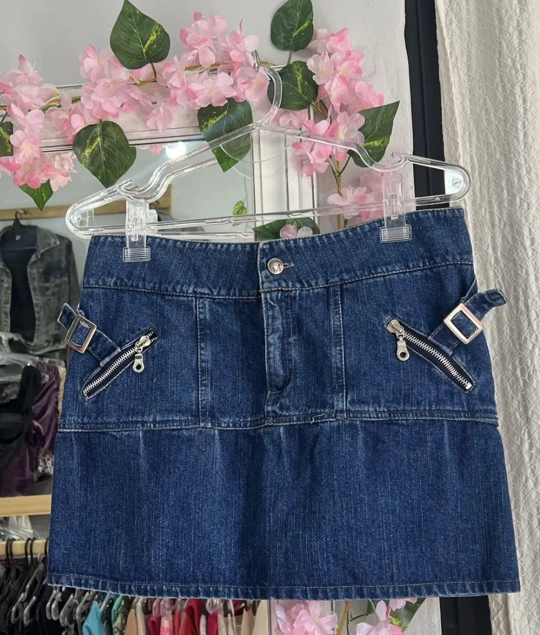 Minifalda de jean azul oscuro con detalles Y2K. Posee bolsillos con cierre y hebillas decorativas. Ideal para un look retro y canchero.