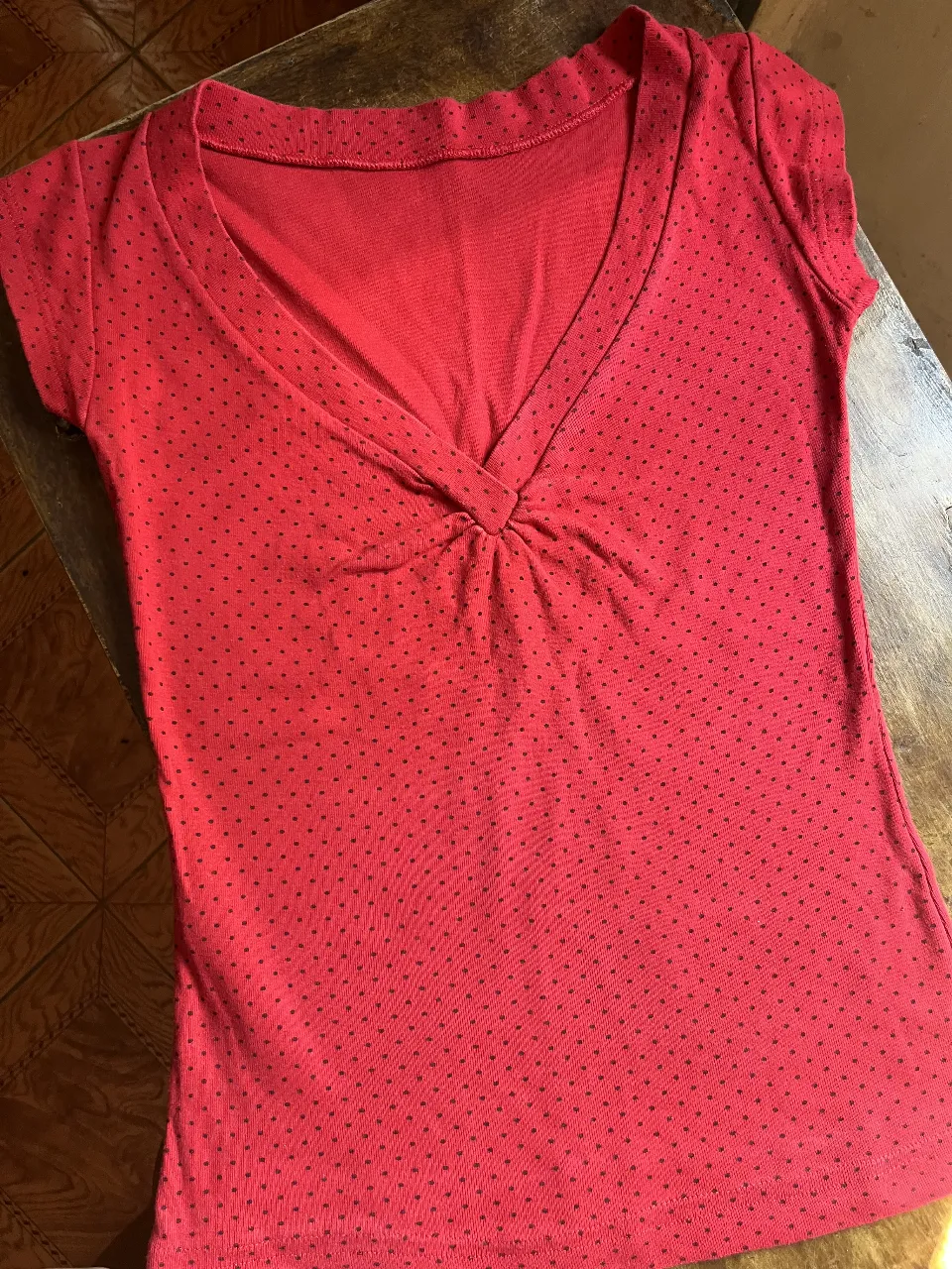 Remera roja con detalles de lunares, escote en V y mangas cortas. Ideal para un look casual y cómodo.