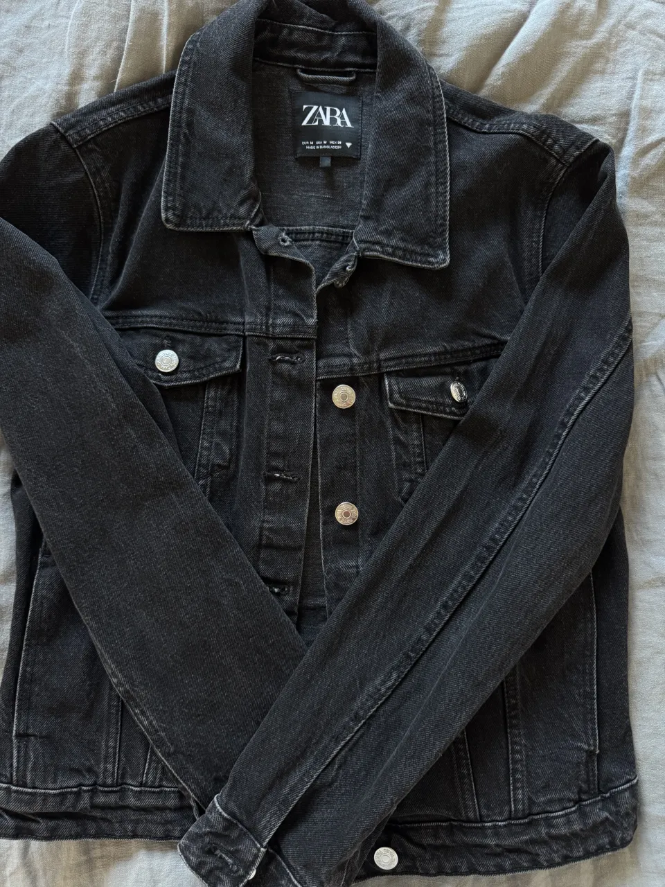 Campera de jean negra con botones metálicos y bolsillos frontales.