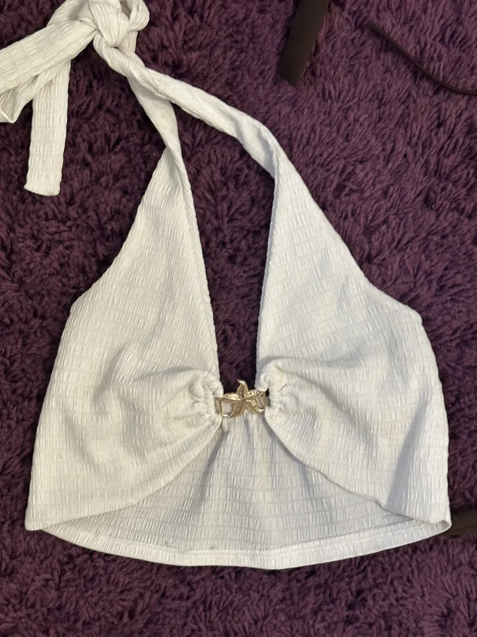 Conjunto de dos piezas blanco, top con breteles finos y detalle de fruncido en el busto con un broche en forma de estrella de mar. Short tiro alto con textura.