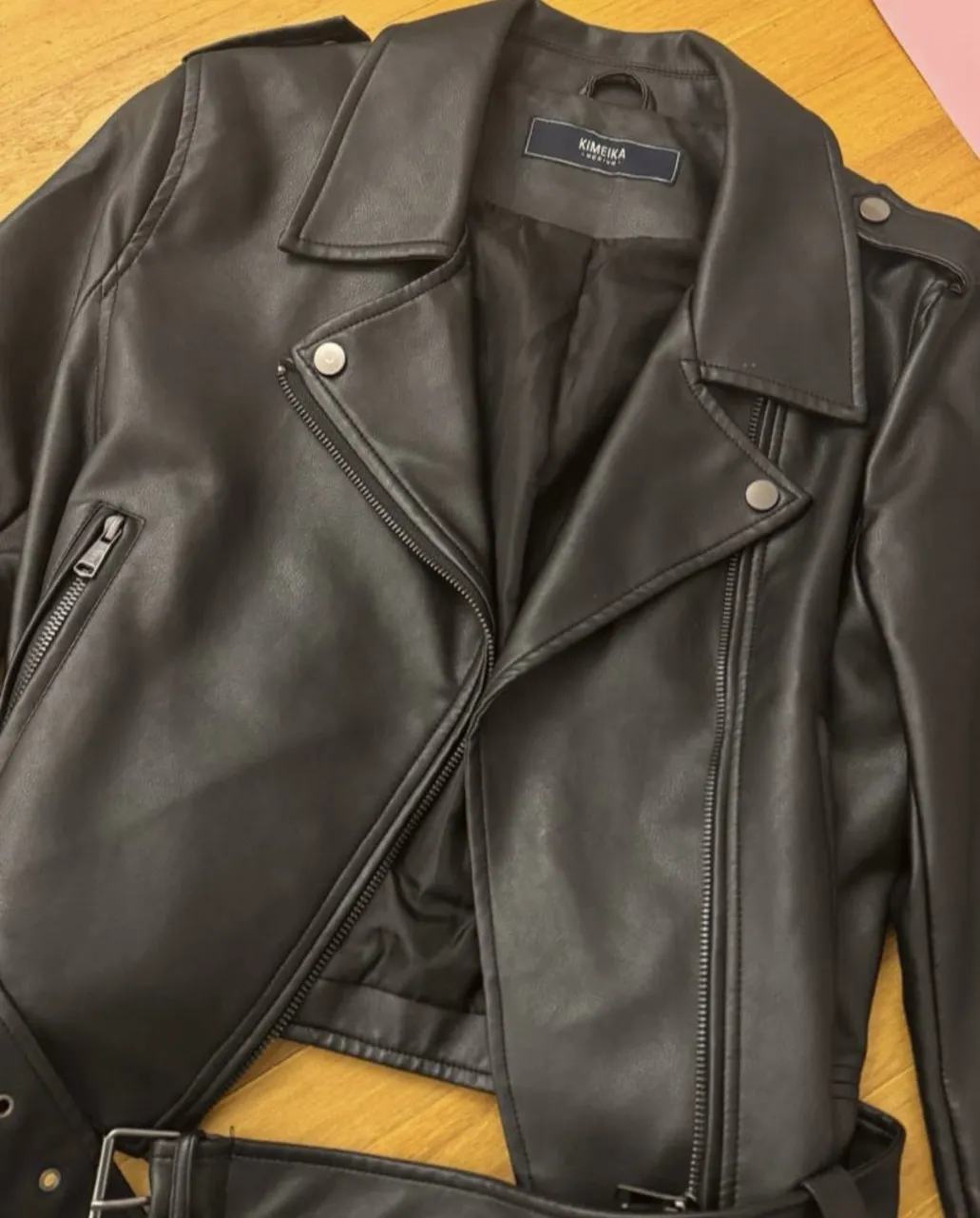 Campera de cuero negra con cuello solapa, cierre al frente y cinturón con hebilla.