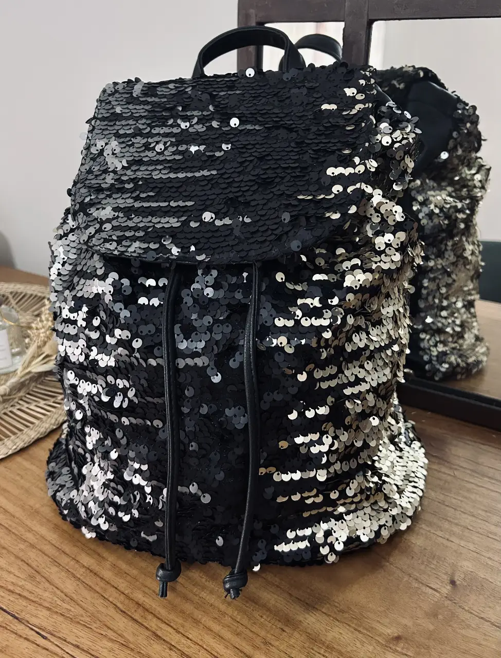 Mochila de mujer con lentejuelas en color negro, dorado y plateado. Posterior símil cuero. Diseño moderno y llamativo, ideal para un look de fiesta o para darle un toque especial a tu outfit diario. Cuenta con correas ajustables y un compartimento principal espacioso.