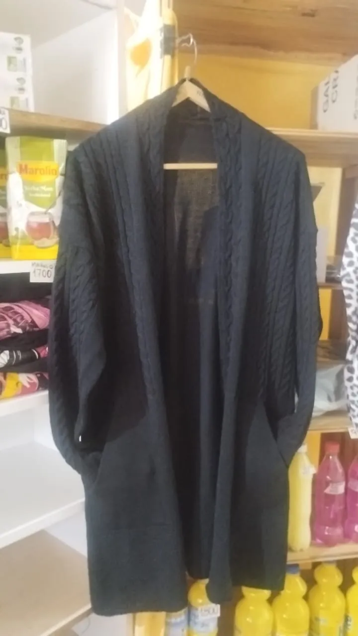 Cardigan largo de tejido con trenzas y bolsillos. Se abre al frente.