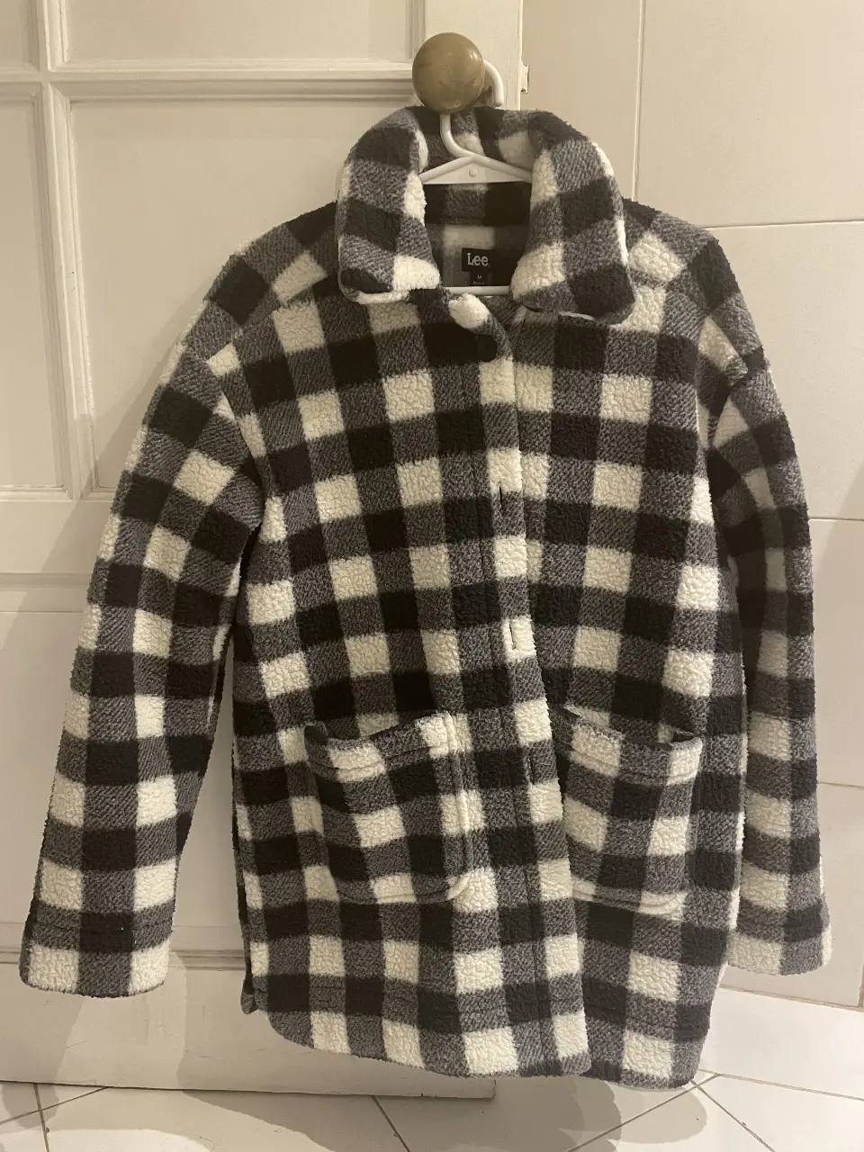 Campera de abrigo con diseño a cuadros en blanco y negro, estilo sherpa. Tiene un único uso. Ideal para un look casual y abrigado.