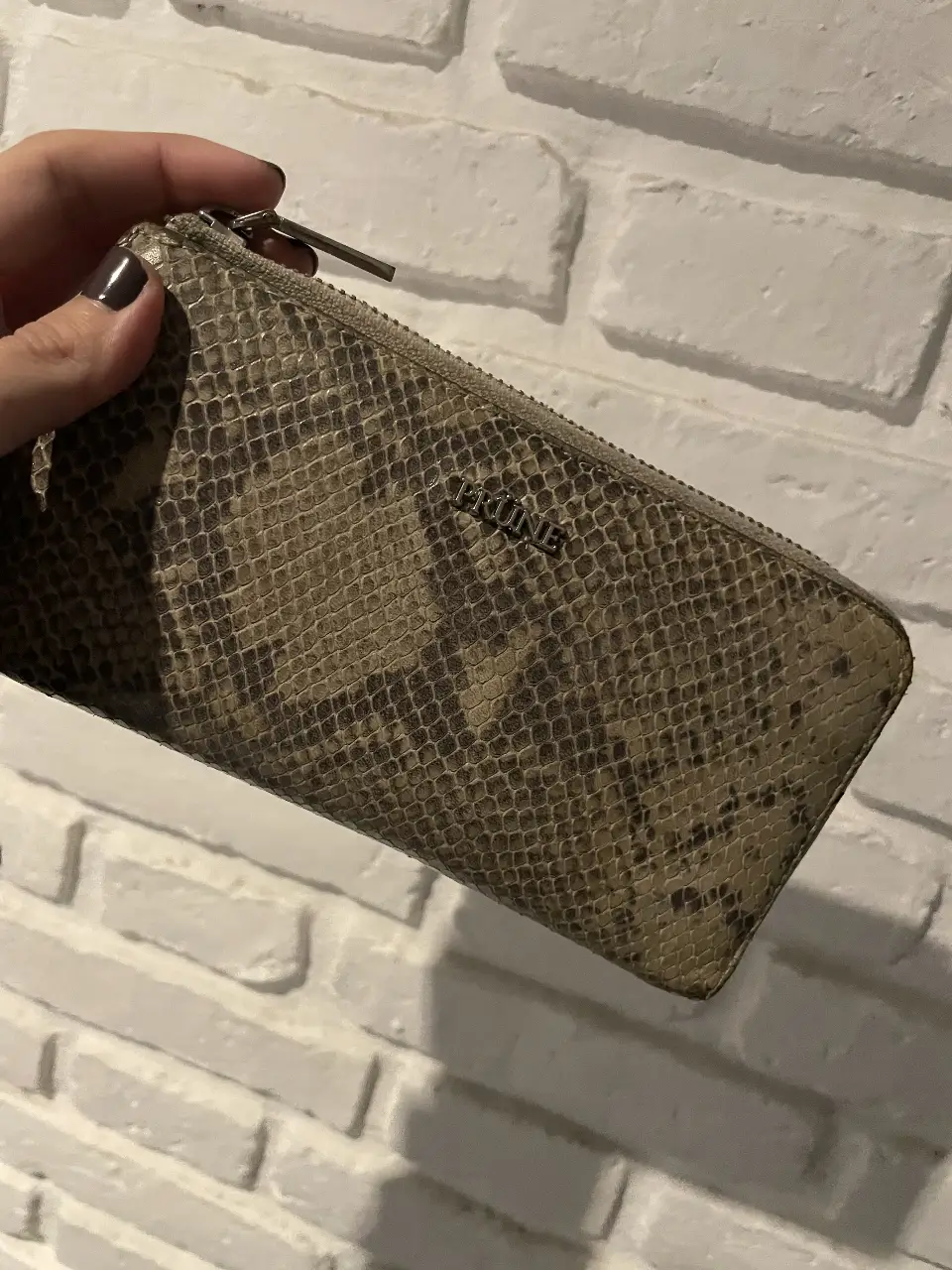 Billetera de cuero con estampado de serpiente, ideal para llevar tus esenciales con estilo. Cuenta con cierre y un interior rosa que le da un toque de color y originalidad.