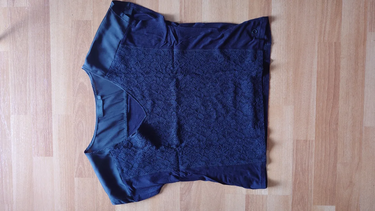 Blusa de mujer negra con detalles de encaje en el frente. Ideal para un look elegante y sofisticado.