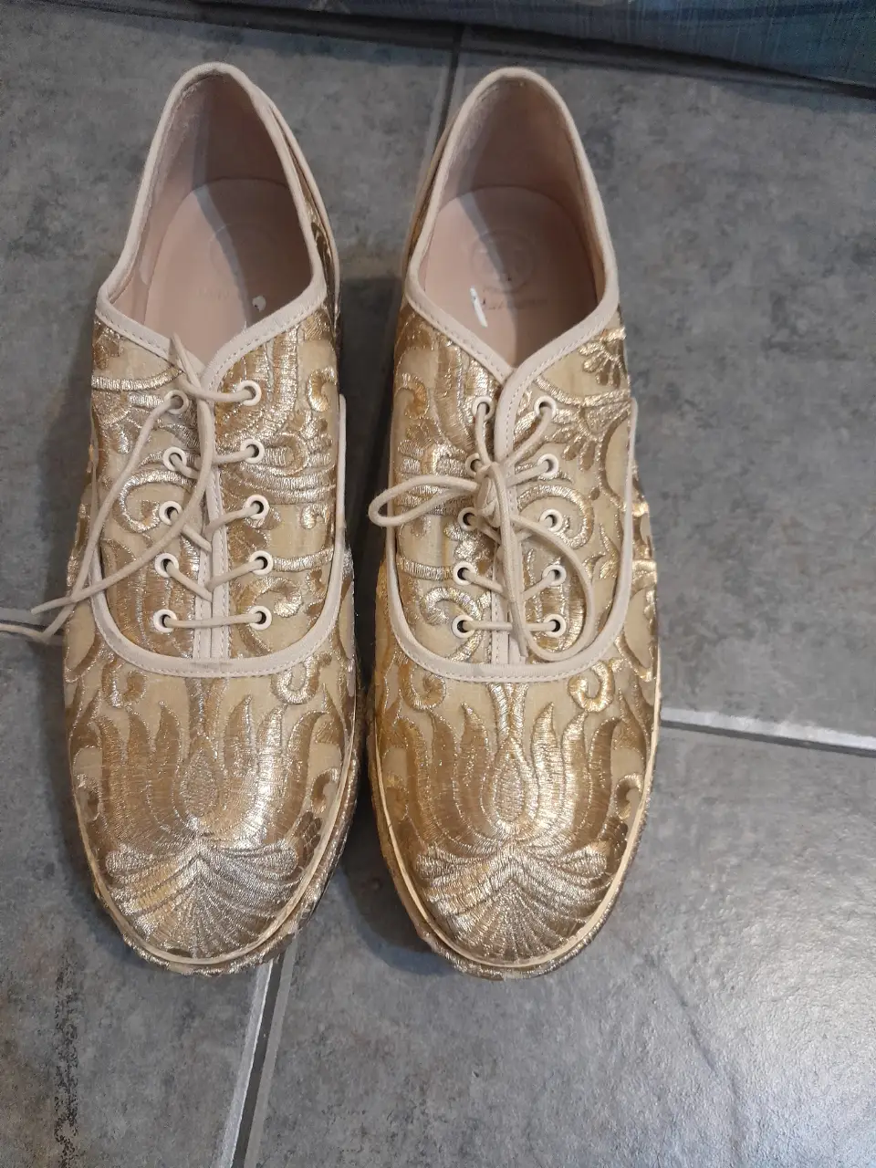 Zapatos de fiesta dorados con bordado floral de la marca Tory Burch. Ideales para eventos especiales.