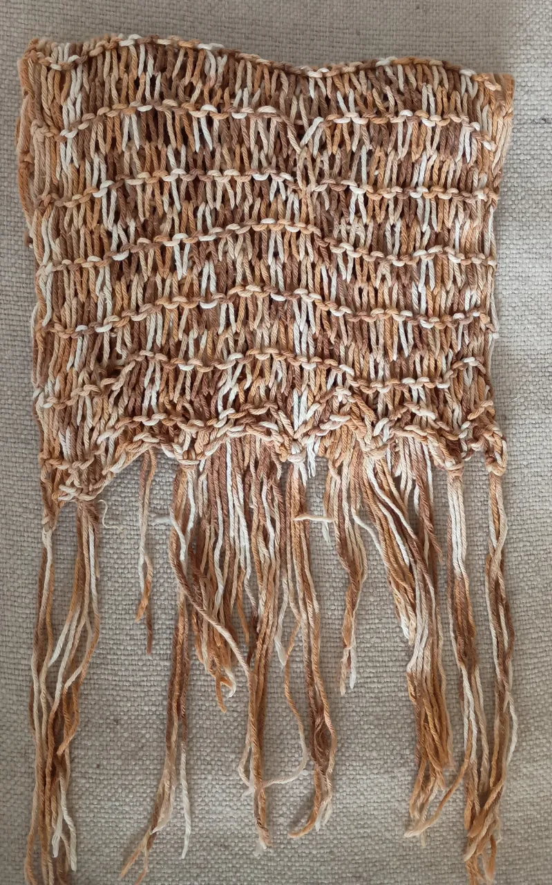 Bufanda tejida a mano en tonos crudo y ocres, ideal para complementar cualquier look. Diseño artesanal y versátil.