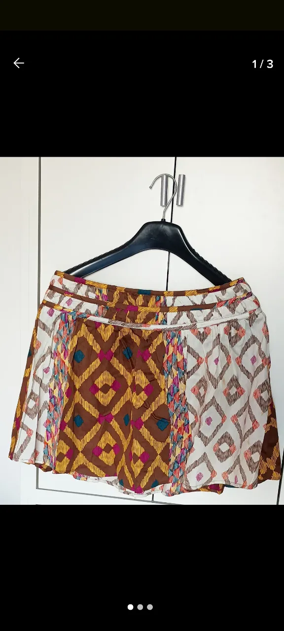 Pollera con estampado geométrico en tonos marrones, amarillos, blancos y detalles en fucsia y azul. Diseño bohemio y vibrante, ideal para un look casual y con estilo.