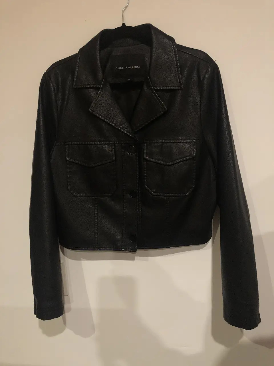 Campera estilo biker de cuero sintético negro, con dos bolsillos delanteros y botones. Ideal para un look casual y moderno.