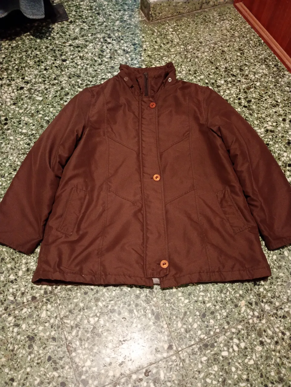 Campera marrón de abrigo, ideal para el frío. Posee botones a tono y cuello alto con cierre.