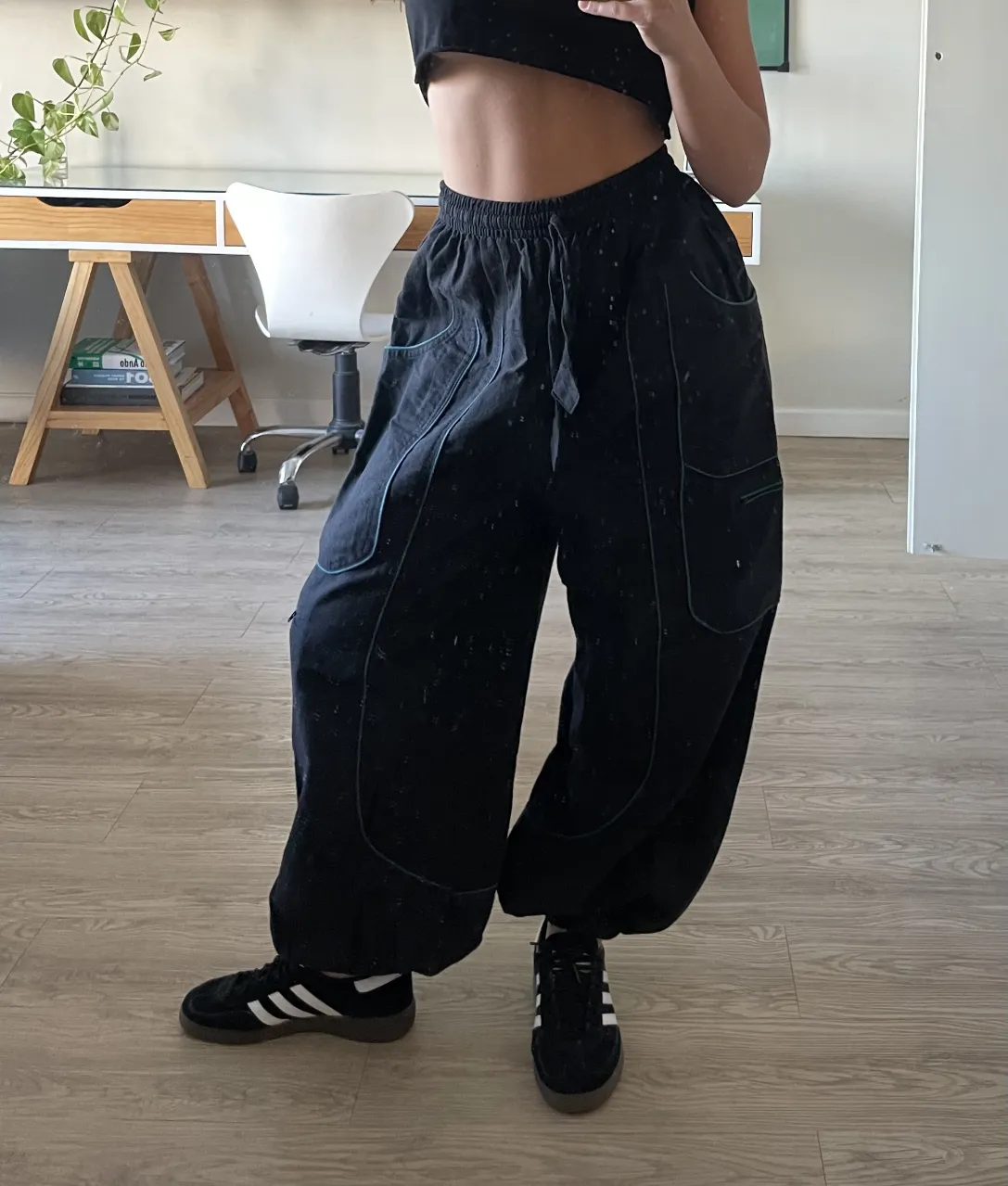 Pantalón negro ancho con detalles de costura en verde. Comprado en un vintage en Barcelona. Posee bolsillos amplios y cordón ajustable en la cintura. Ideal para un look urbano y cómodo.