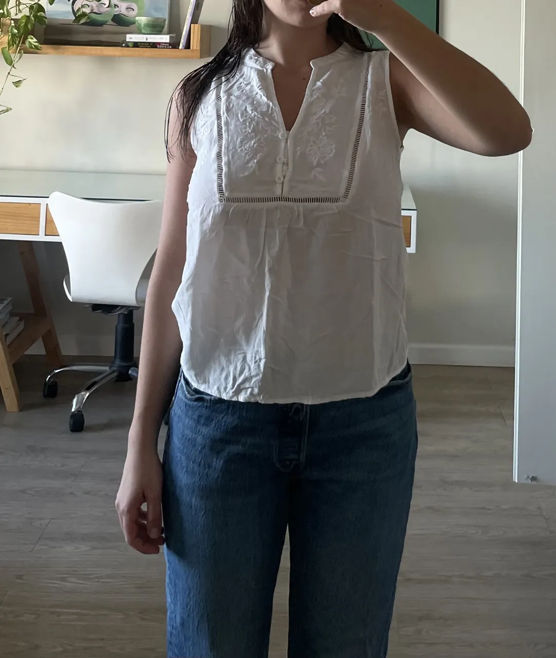 Remera blanca sin mangas con detalles bordados y botones en el escote. Perfecta para un look fresco y casual.