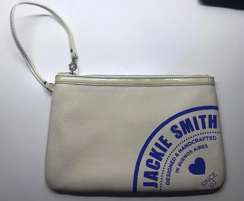 Clutch Jackie Smith blanco con logo azul. Diseño artesanal y detalles de calidad. Ideal para llevar lo esencial con estilo.