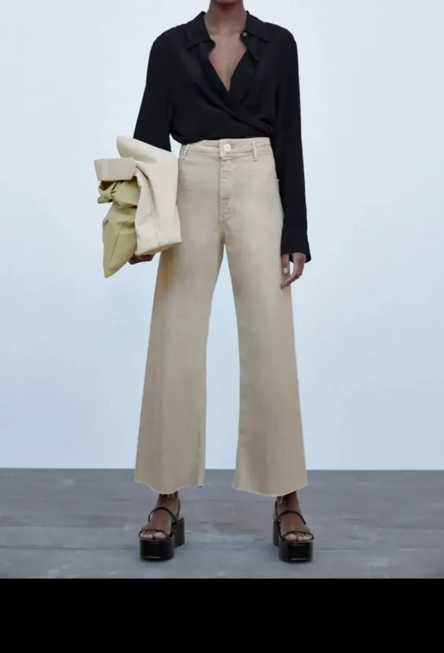 Pantalón ancho de color crudo, con bolsillos y cierre.