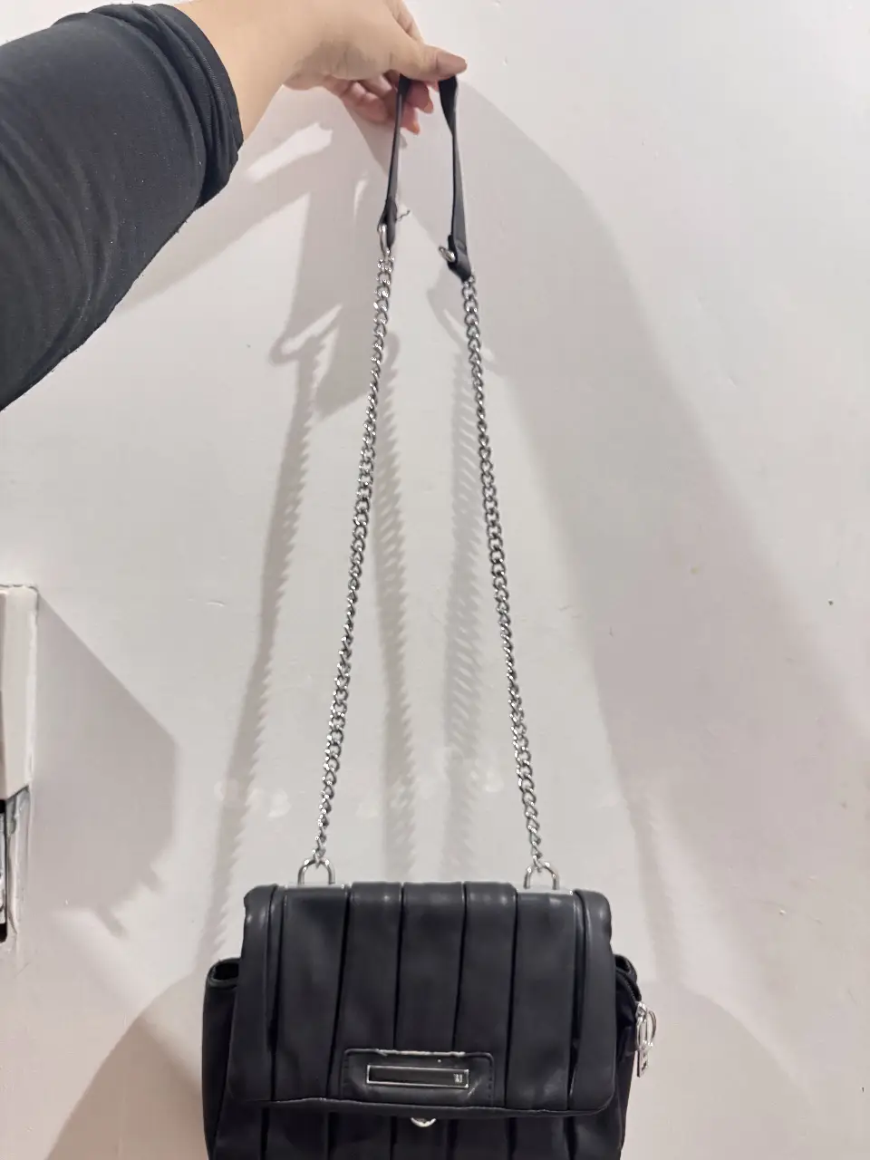 Cartera negra con diseño plisado y cadena plateada. Ideal para un look elegante y moderno.