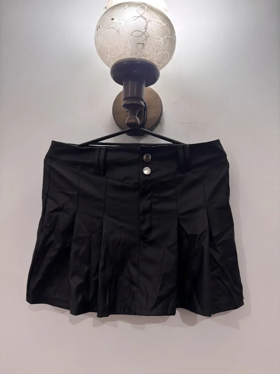Minifalda negra de cuero sintético con detalles de botones y pliegues. Ideal para un look Y2K o rocker.