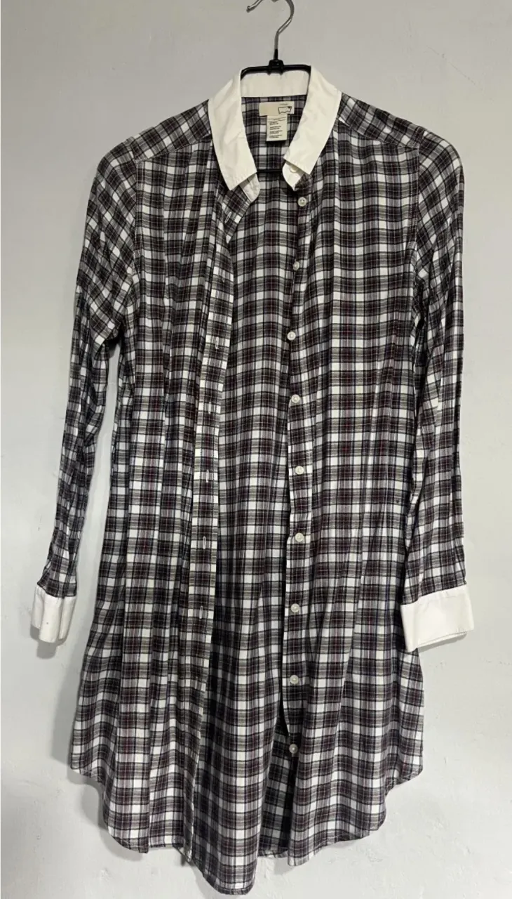 Camisa a cuadros de manga larga con cuello blanco y puños blancos. Se abotona al frente.