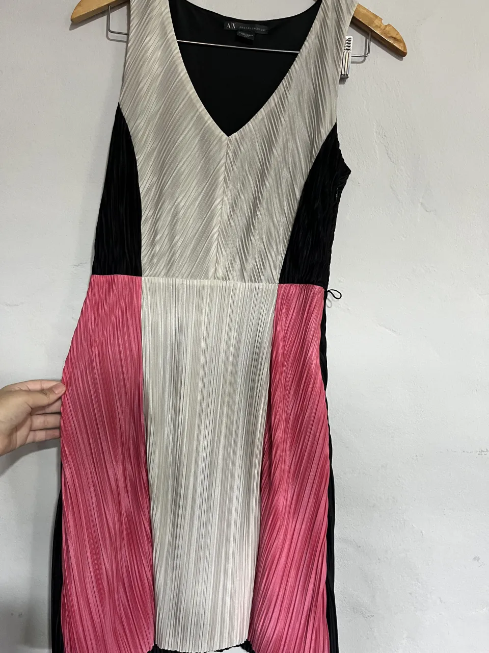 Vestido midi de fiesta, con un diseño moderno y elegante. Presenta un corte asimétrico y detalles plisados en la falda, combinando colores vibrantes como el rosa y el blanco con bloques de negro. Ideal para eventos especiales o salidas nocturnas.