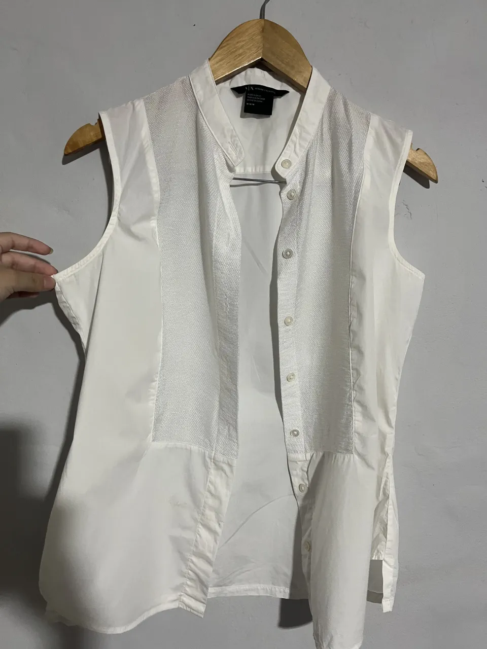 Camisa blanca sin mangas, con cuello mao y botones al frente. Posee un detalle de textura en la parte delantera central. Ideal para un look casual o de trabajo.