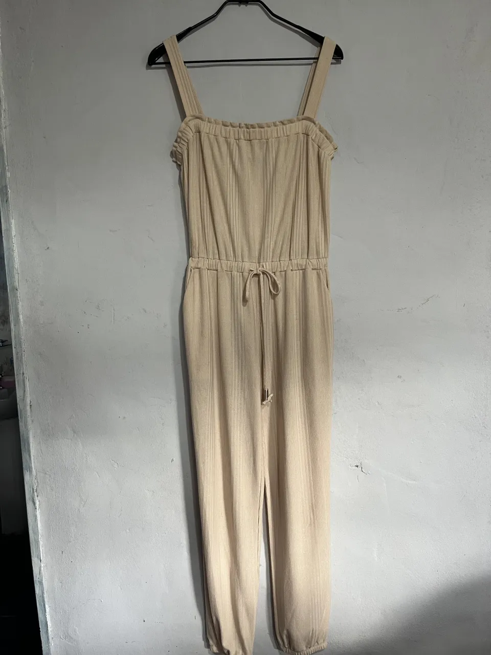 Mono largo de tela acanalada color crudo. Tiene tirantes finos, cintura elastizada con cordón ajustable y puños en los tobillos. Súper cómodo y canchero, ideal para el día a día.