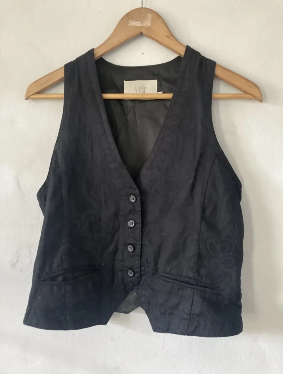 Chaleco negro con textura sutil y botones al frente. Un básico versátil para elevar cualquier look.