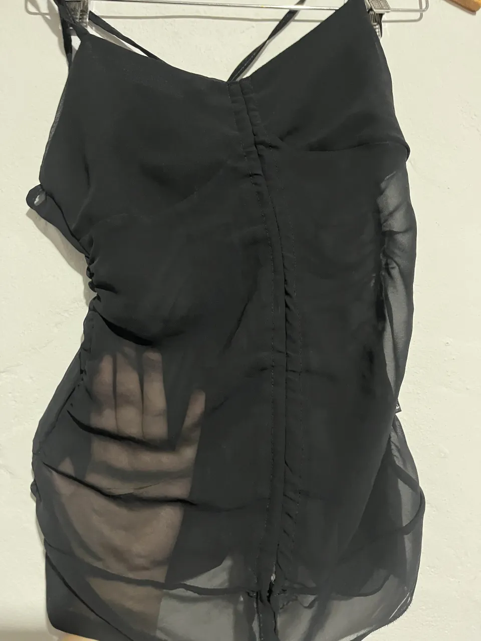 Top negro con detalles de fruncido y tiras cruzadas. Ideal para un look canchero y sensual.