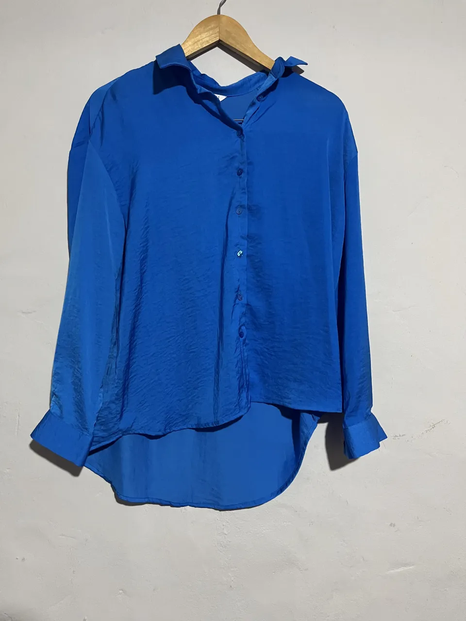 Camisa de seda azul vibrante, con botones al frente y un corte moderno. Perfecta para un look elegante y canchero.