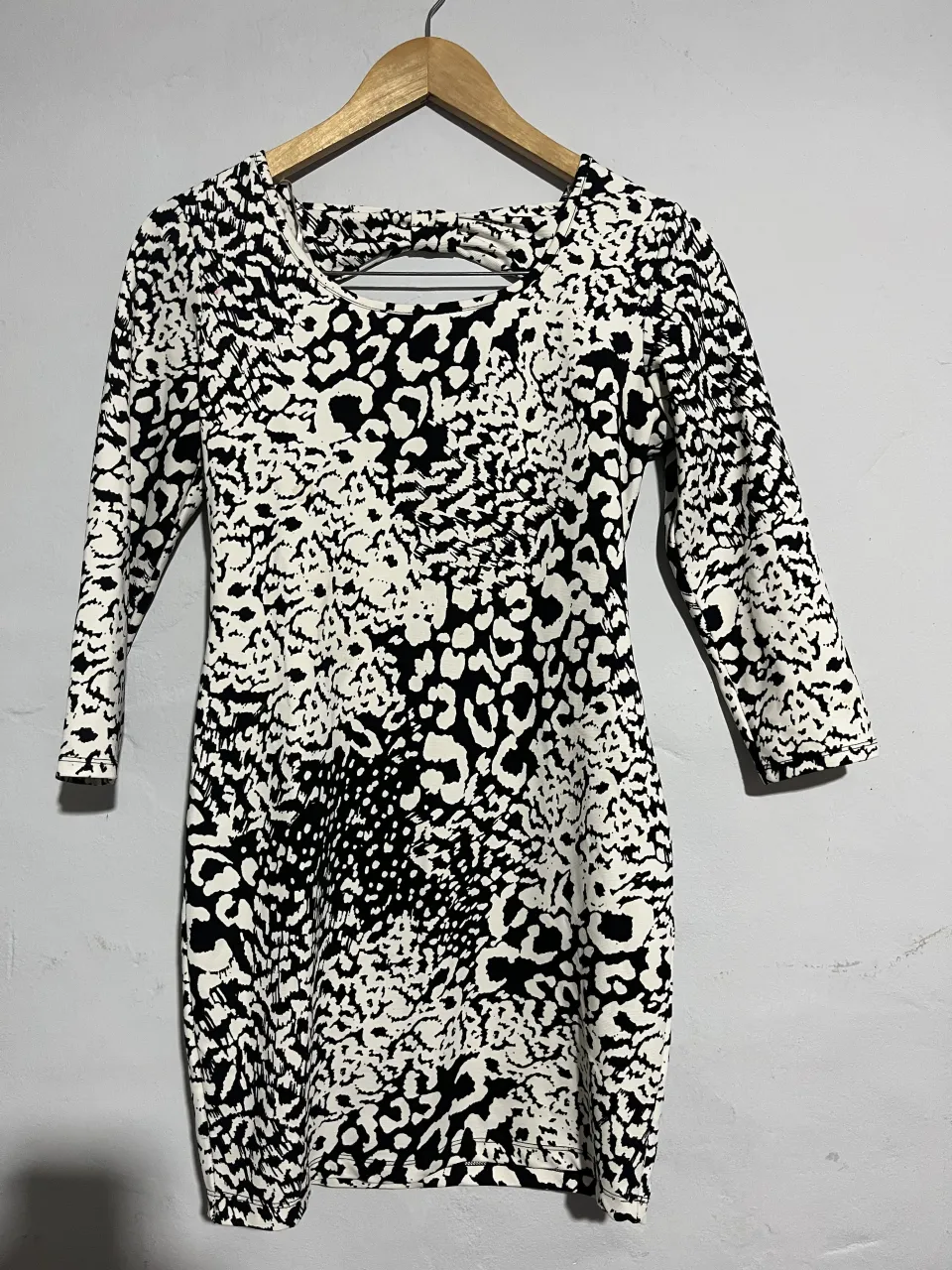 Vestido corto con estampado animal print en blanco y negro. Posee mangas 3/4 y un detalle de lazo en la espalda. Ideal para un look canchero y moderno.