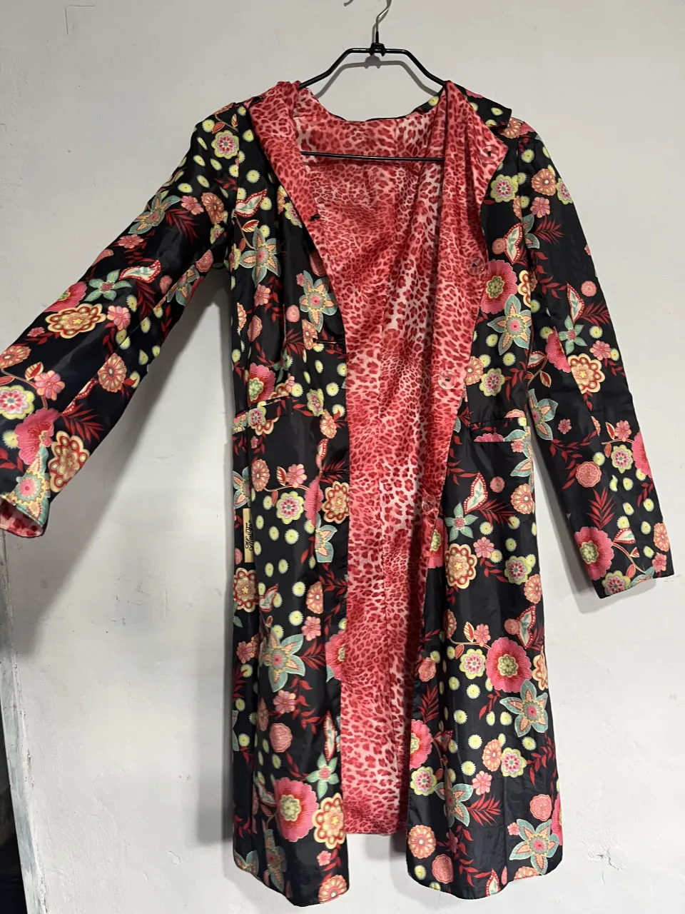 Abrigo reversible con estampado de leopardo y flores. Un lado es rosa con estampado de leopardo y el otro es negro con flores vibrantes. Ideal para darle un toque audaz a tu look.