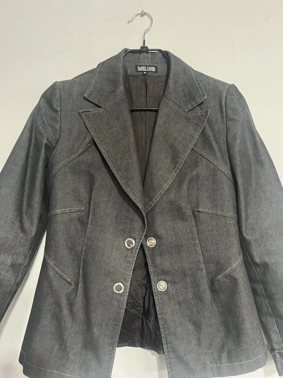 Blazer de jean gris oscuro, con dos botones al frente y bolsillos con solapa. Un clásico que no puede faltar en tu guardarropa.