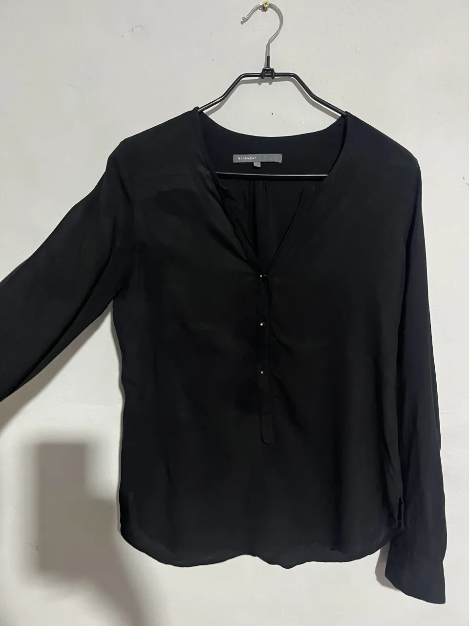 Blusa negra de manga larga, con escote en V y detalles de botones en el frente. Perfecta para un look elegante y sofisticado.