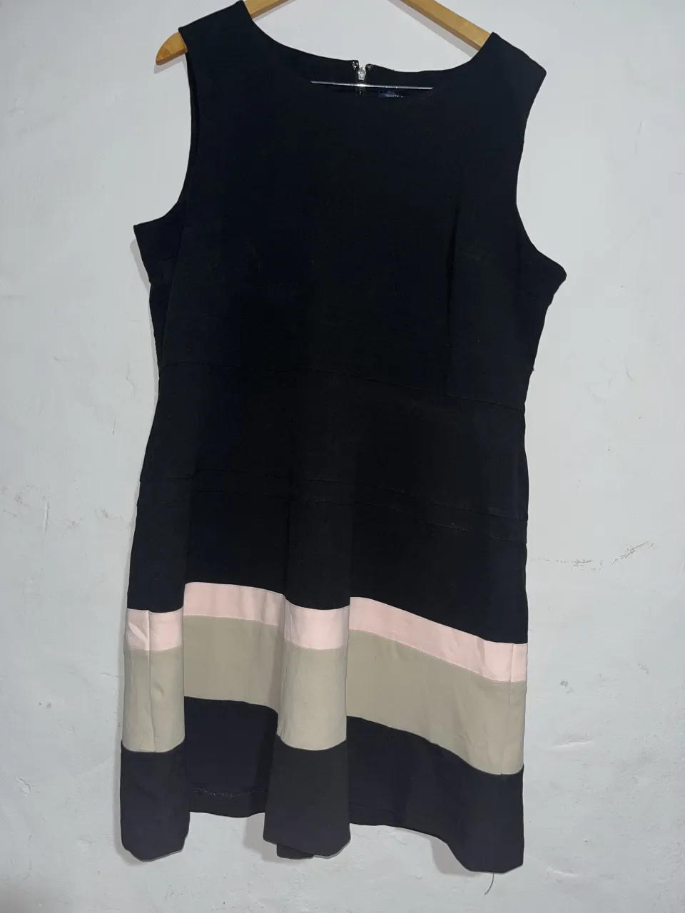 Vestido negro sin mangas con detalles de bloques de color en la falda. Presenta un cierre frontal y un diseño elegante, ideal para ocasiones especiales o para un look sofisticado.