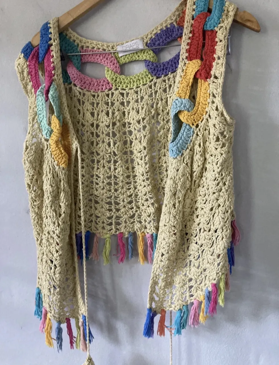 Chaleco tejido al crochet, súper canchero y original. Tiene detalles de eslabones tejidos en colores vibrantes en el cuello y los hombros, y flecos coloridos en el borde inferior. Ideal para darle un toque boho y divertido a cualquier outfit.